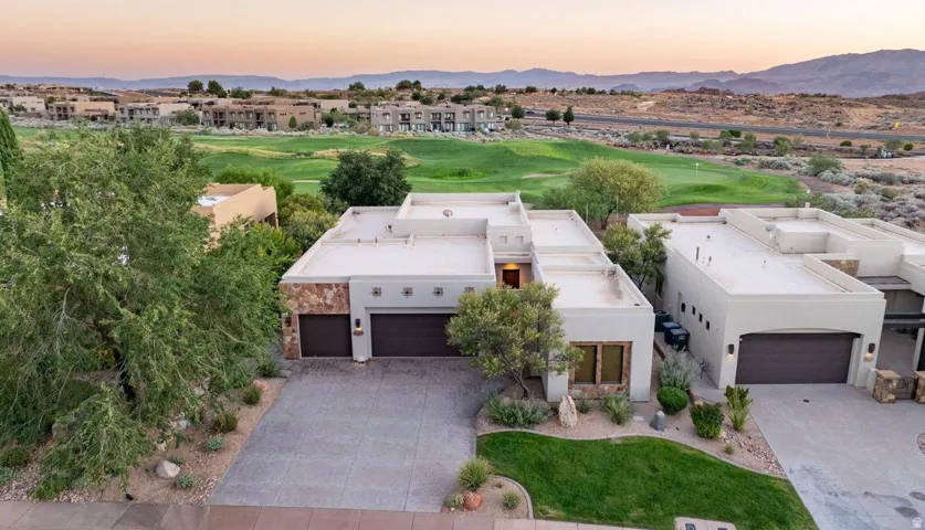 Stucco exterior with stone accents, integrated two-car garage, and landscaped front yard