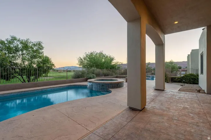 Covered patio with stamped concrete flooring, integrated swimming pool, and raised spa with a waterfall feature