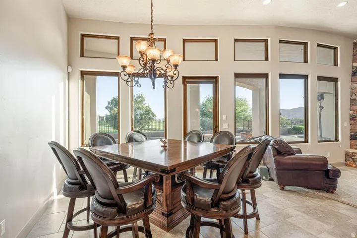Floor-to-ceiling windows with brown frames, tile flooring, and a wrought iron chandelier
