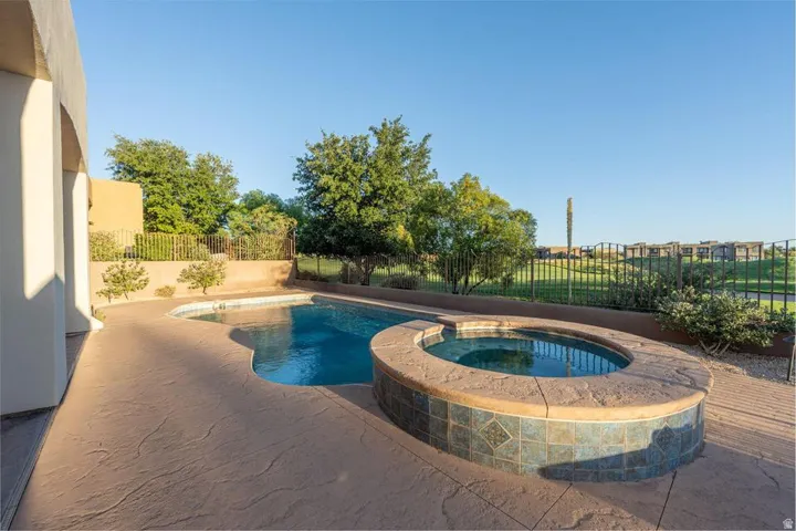 Outdoor pool with integrated spa, stamped concrete decking, and decorative tile accents