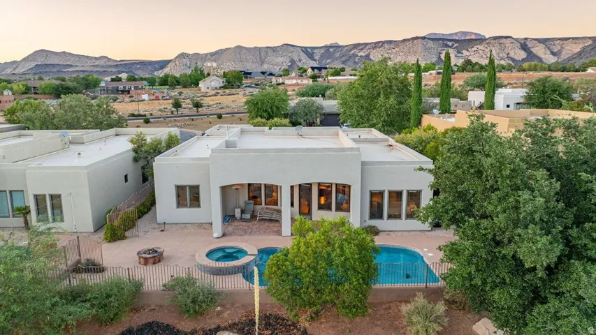 Stucco exterior, covered patio, integrated spa, fenced swimming pool, and mountain backdrop