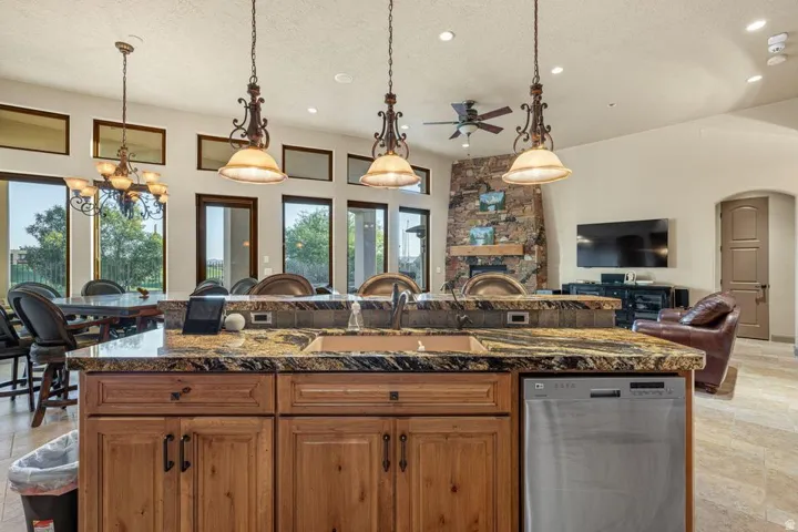 Kitchen island with granite countertops, integrated sink, and stainless steel dishwasher