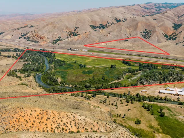 Expansive property featuring a winding river, dense tree coverage, a large building with multiple wings, and surrounding mountainous terrain