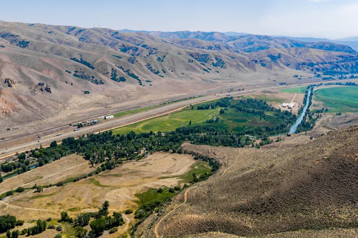 Expansive valley landscape with a river, highway, and varied terrain