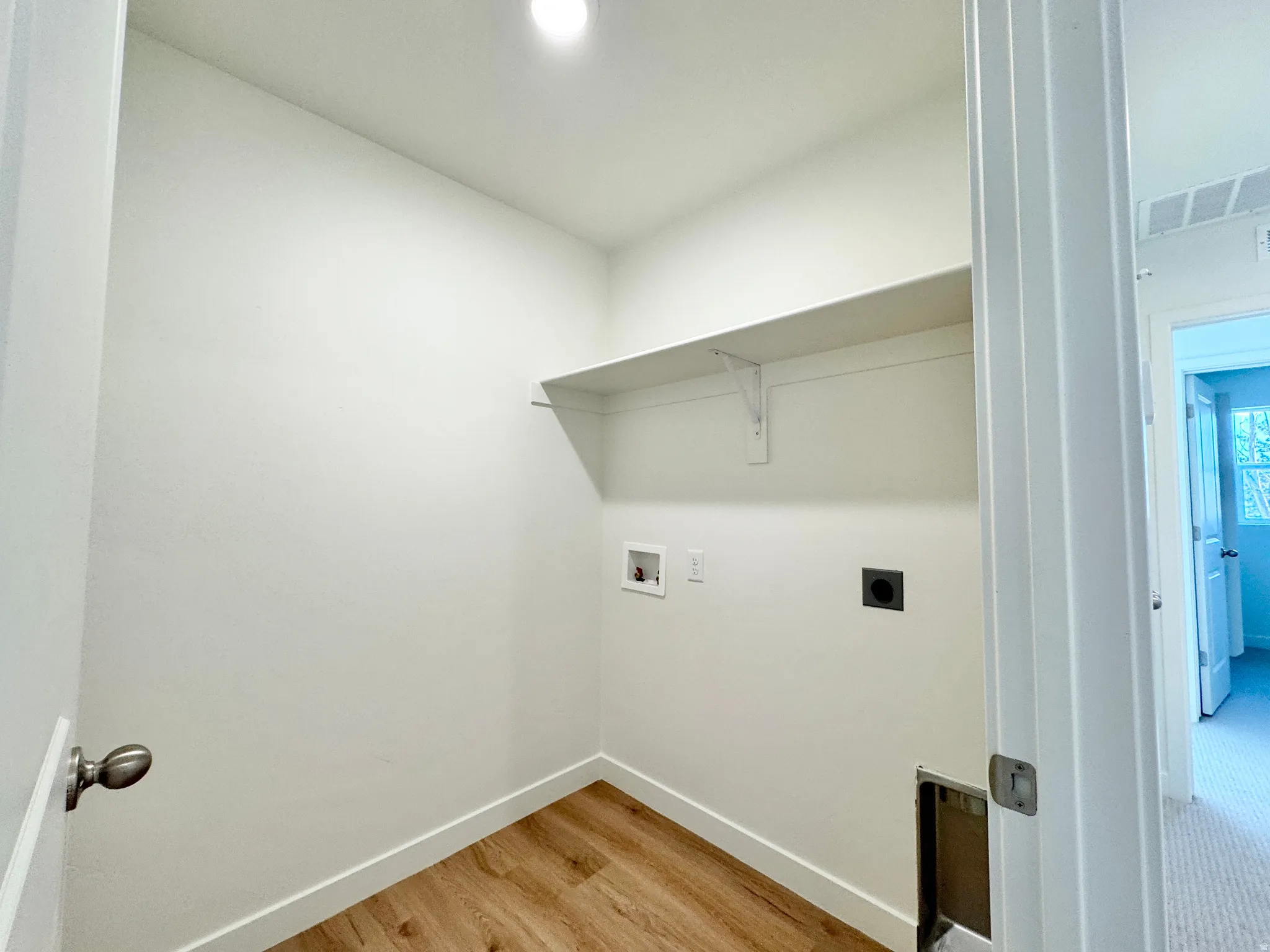 Dedicated utility space featuring wood-finish flooring, a built-in shelf, and recessed lighting