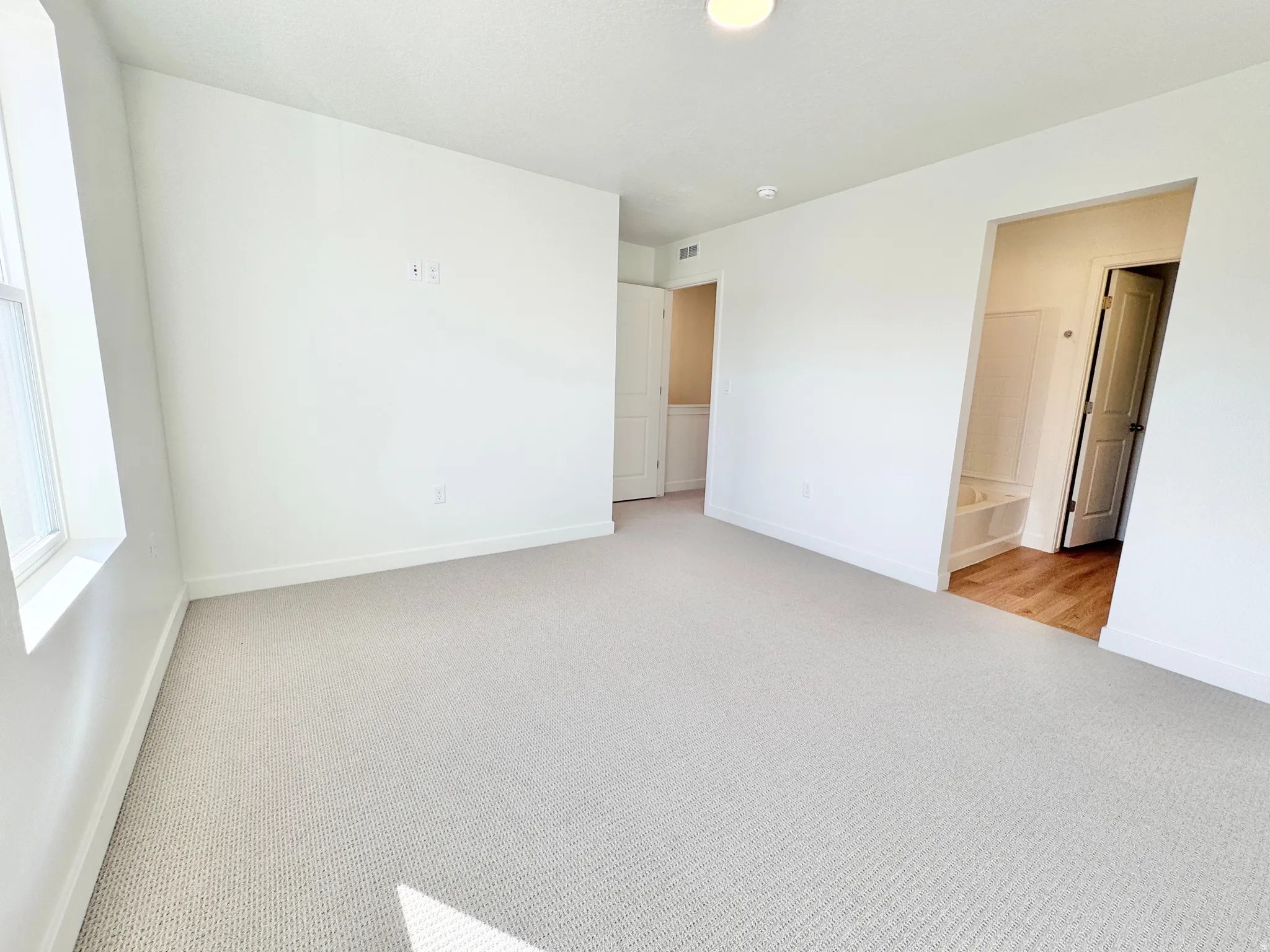 Light-filled room featuring neutral wall paint, textured carpeting, and a recessed ceiling light