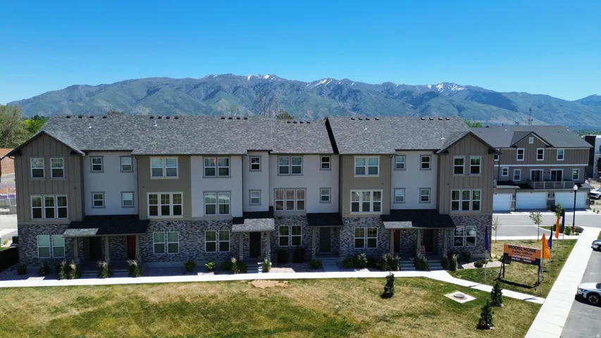 Townhome exterior featuring stone accents, multiple windows, and a gray shingle roof