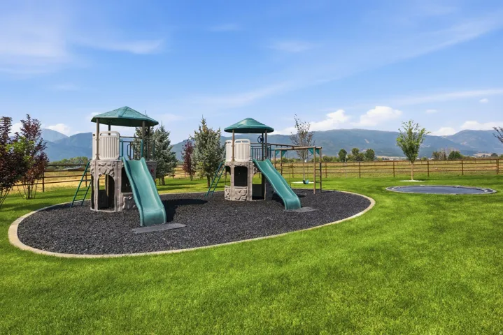 Expansive green lawn with a playground featuring two slides and swing set