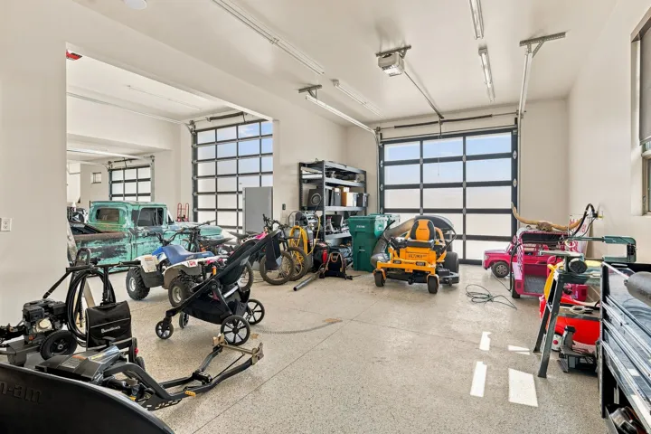 Attached two-car garage with multiple overhead doors and a high ceiling