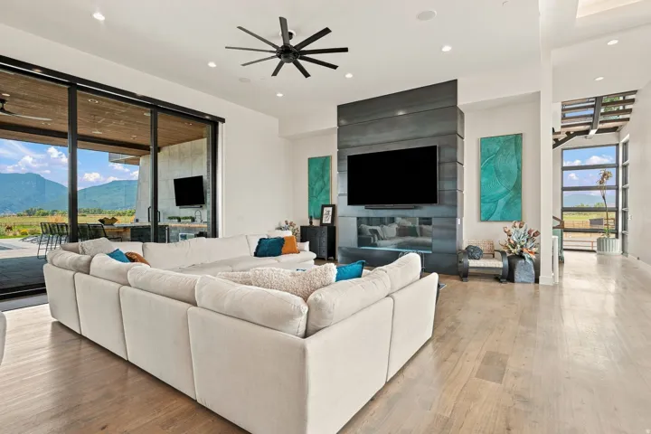 Expansive living area featuring light wood-finish flooring, a contemporary ceiling fan, and recessed lighting