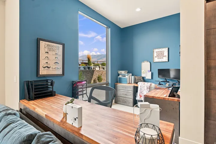 Expansive window, recessed lighting, wood-finish desktop, blue accent wall