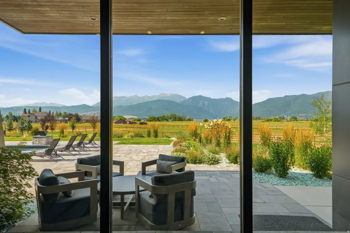 Expansive outdoor patio with stone pavers, integrated landscaping, and a fire pit feature