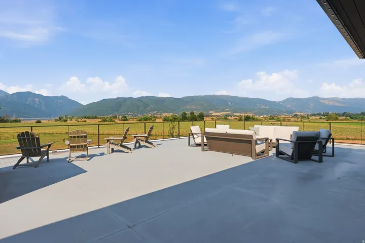 Expansive patio with durable concrete surfacing, perimeter railing, and mountain backdrop