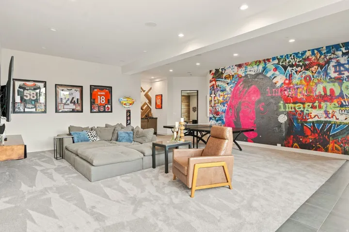 Recessed lighting illuminates the open-concept room featuring patterned carpeting and a full-wall mural