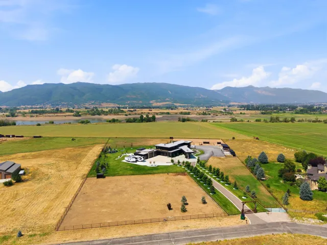 Expansive property featuring a contemporary residence, a paved driveway with a gate, and extensive natural landscaping