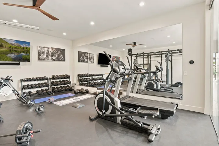 Fitness room featuring rubber flooring, recessed lighting, and a large wall-mounted mirror