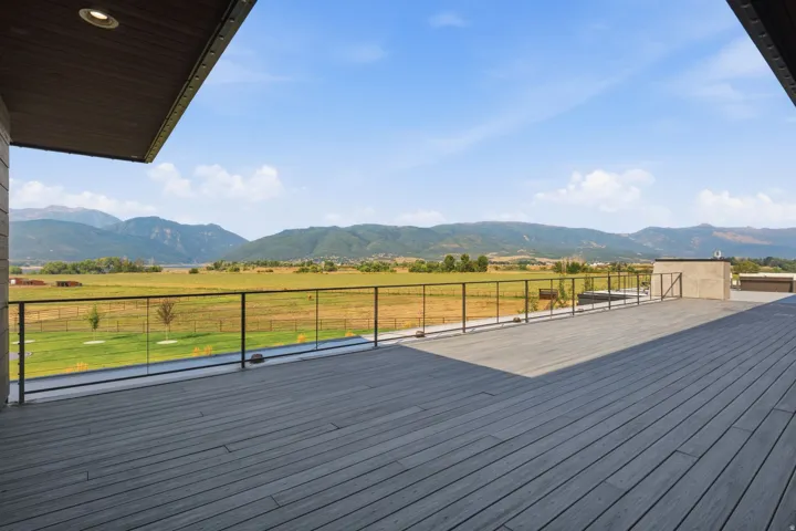 Expansive outdoor deck featuring composite decking, glass panel railing, and recessed lighting