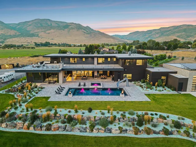 Modern exterior with expansive patio, integrated swimming pool with slide, and surrounding rock landscaping