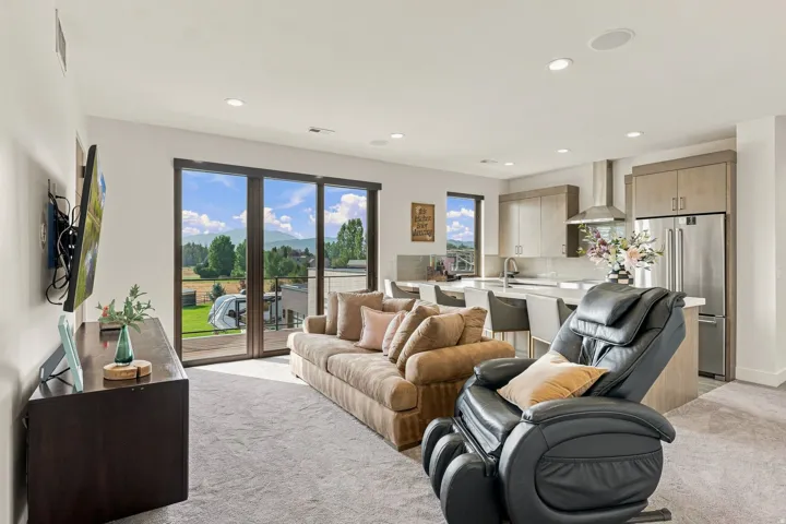 Open-concept living space with expansive sliding glass doors, recessed lighting, and light-toned carpeting