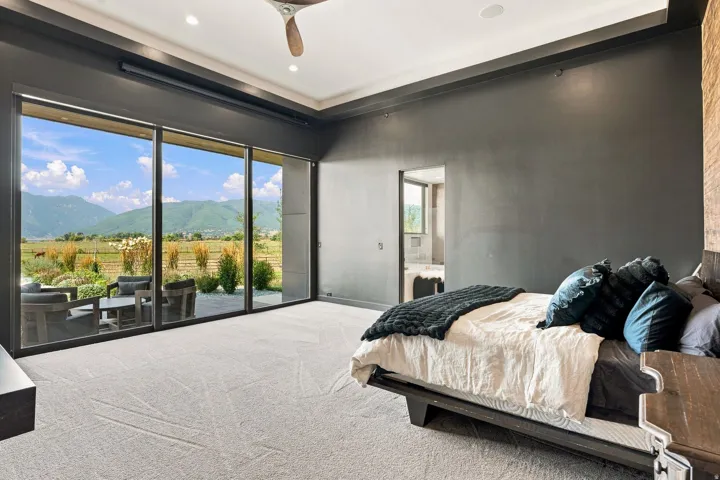 Expansive wall-to-wall glass doors, recessed lighting, ceiling fan, carpeted flooring, and an open doorway leading to an adjoining room