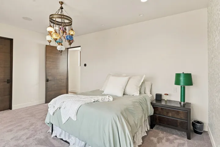 Recessed lighting, ornate chandelier, wood-finish doors, and textured accent wall