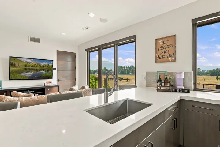 Expansive counter space with integrated sink, contemporary cabinetry, recessed lighting, and large windows with mountain scenery