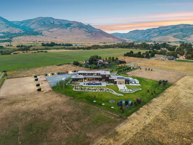 Contemporary architectural design, extensive manicured lawn, dedicated equestrian facilities, outdoor swimming pool, and mountain backdrop
