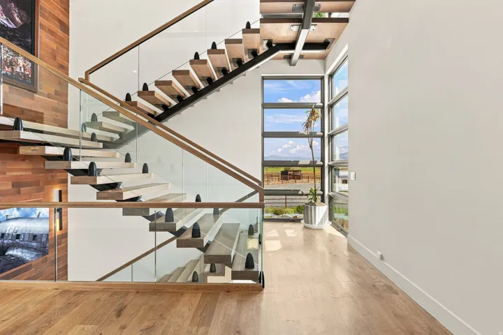 Floating wood stair treads with glass railings, wood-finish flooring, and multi-pane windows