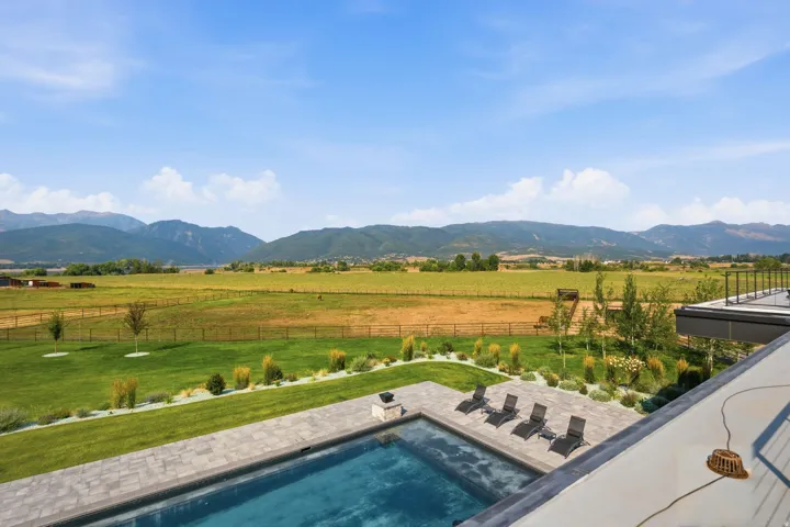 Expansive outdoor living area featuring a rectangular pool, paver patio, and manicured lawn