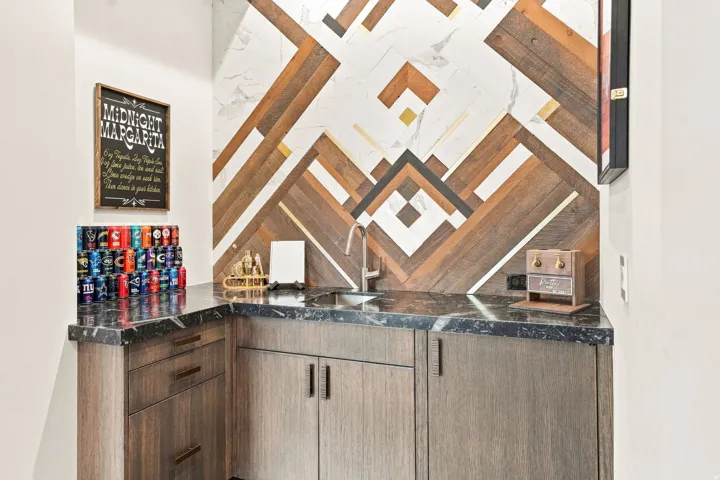 Built-in wet bar featuring dark wood-finish cabinetry and a black countertop
