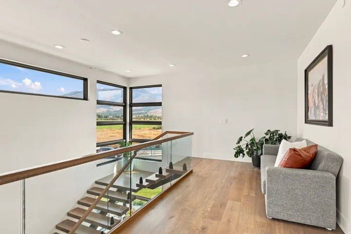 Floating staircase with glass railing and wood-finish handrail