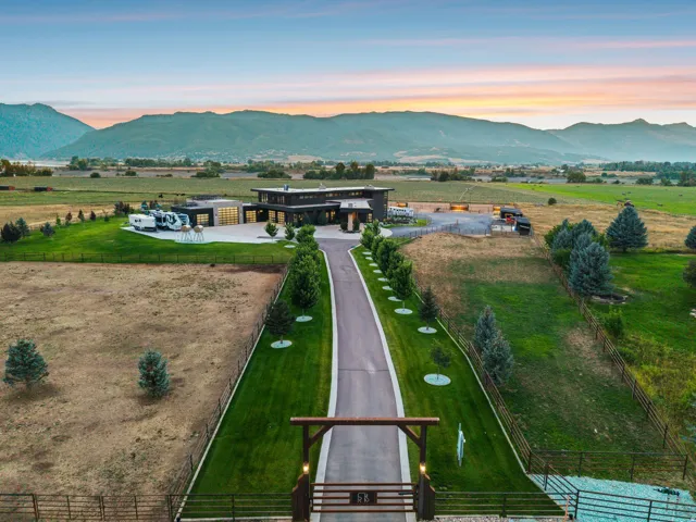 Expansive property featuring a paved entry drive, manicured lawns, a contemporary multi-story residence, and a mountain backdrop