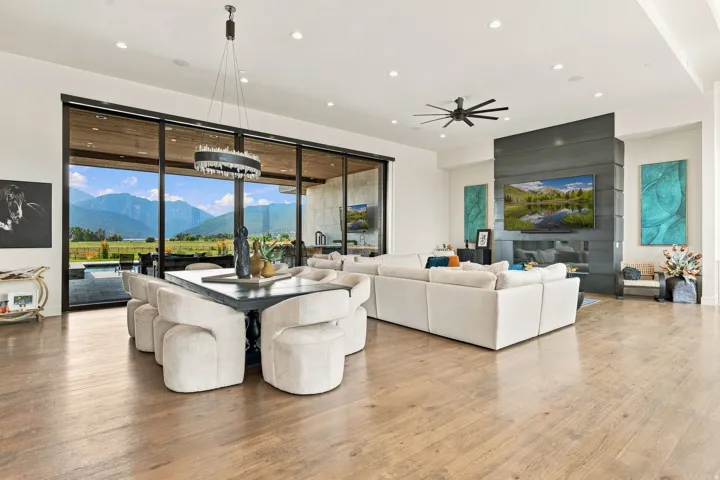 Spacious open-concept interior with wood-finish flooring, a contemporary fireplace, recessed lighting, and expansive glass doors