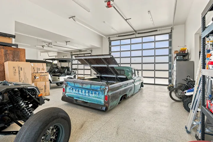 Large garage space with a glass panel overhead door, speckled flooring, and white walls
