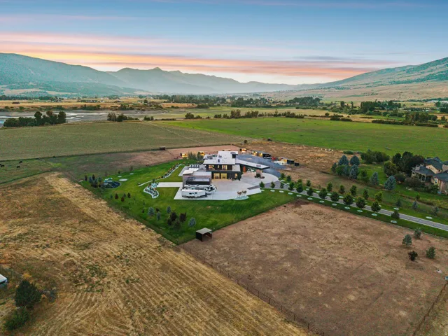 Expansive property featuring a modern architectural residence, a large paved driveway, and manicured landscaping