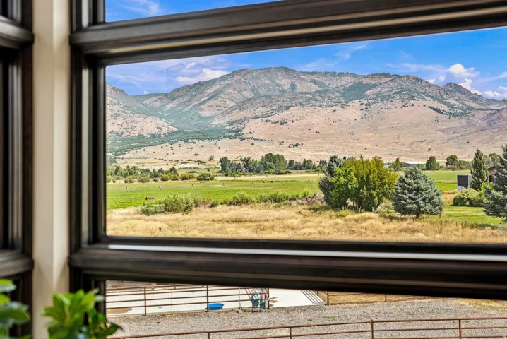 Expansive mountain scenery with distant fields, visible through a large window with dark frames