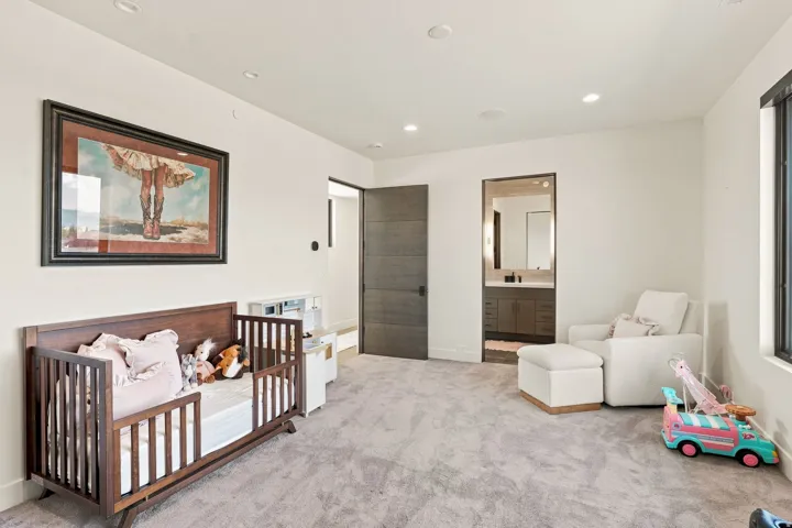 Recessed lighting, light-toned carpeting, a dark wood-finish interior door, and a built-in vanity with a mirror