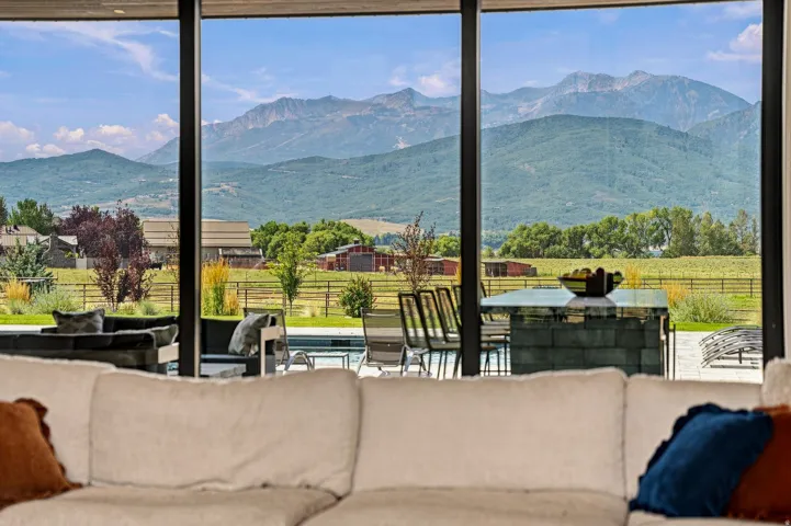 Expansive floor-to-ceiling windows, mountain scenery, outdoor pool, patio area, and built-in outdoor bar