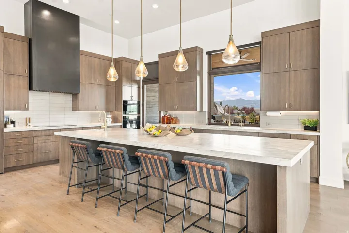 Kitchen featuring extensive cabinetry, a large center island with counter seating, integrated double ovens, and a contemporary range hood