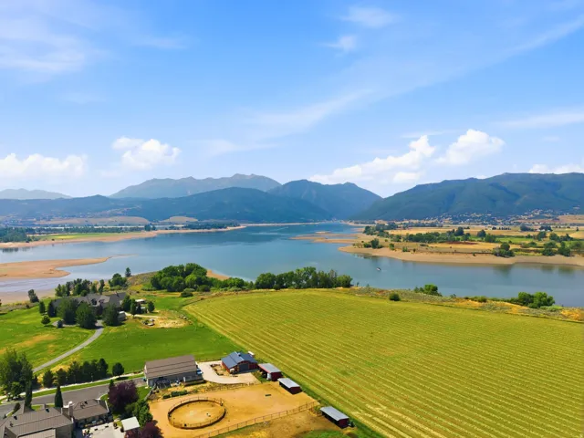 Expansive green fields, adjacent buildings with red roofs, and surrounding mountainous terrain
