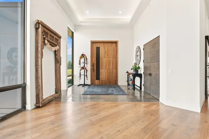 Grand entry foyer with wood-finish flooring, high ceilings with recessed lighting, full-light entry door, and large windows
