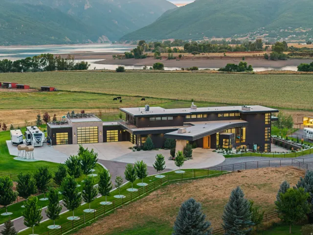 Contemporary architecture with expansive flat roofs, multiple garage bays with frosted glass doors, and a circular driveway