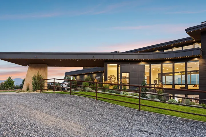 Modern architectural design with a large stone support column, expansive window arrays, and extensive exterior lighting