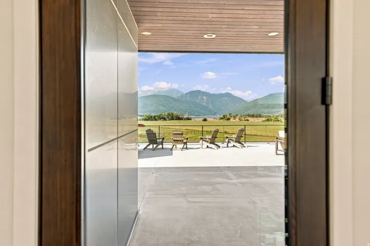 Expansive outdoor patio with concrete flooring, framed by a wood-paneled ceiling with recessed lighting