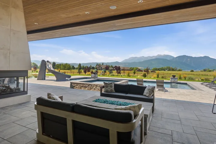 Expansive outdoor living area featuring a built-in fireplace, recessed lighting, and wood-finish ceiling