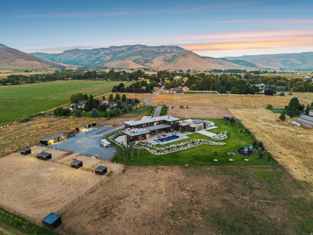 Expansive property featuring a contemporary residence, large swimming pool, manicured lawn, and multiple outbuildings