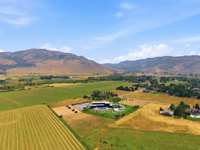 Expansive property with mountainous scenery, featuring a large estate, swimming pool, and cultivated fields