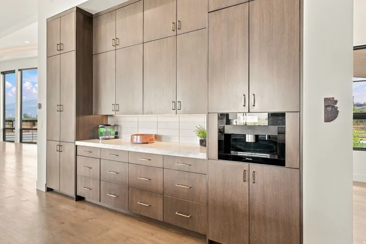 Extensive wood-finish cabinetry with silver-tone hardware, light-toned countertop, and white subway tile backsplash