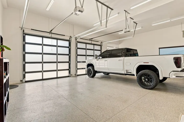 Two-car garage featuring a speckled epoxy floor and translucent paneled garage doors