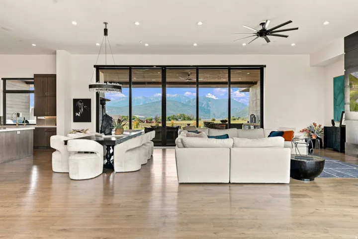 Expansive living area with wood-finish flooring, recessed lighting, and a modern ceiling fan